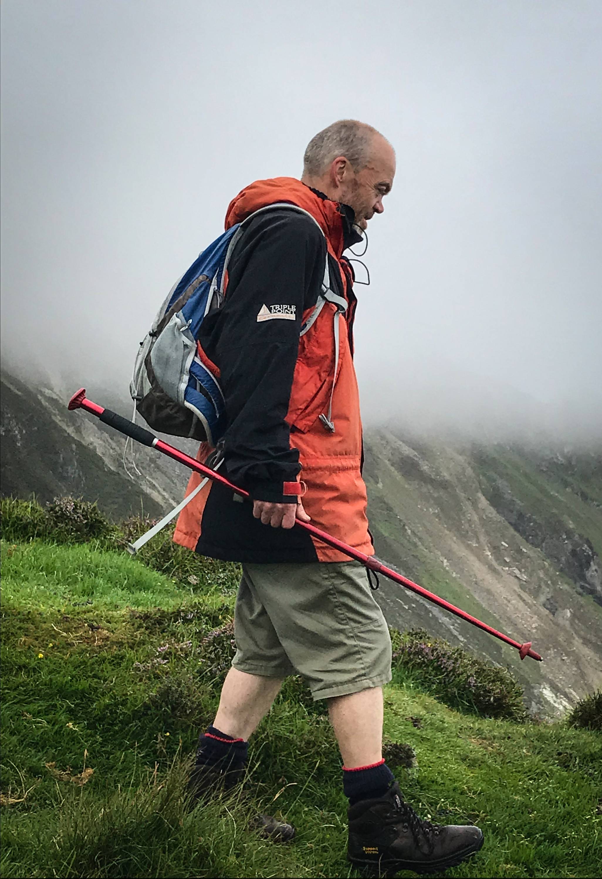 A hill walker in front of a cloud-covered mountain