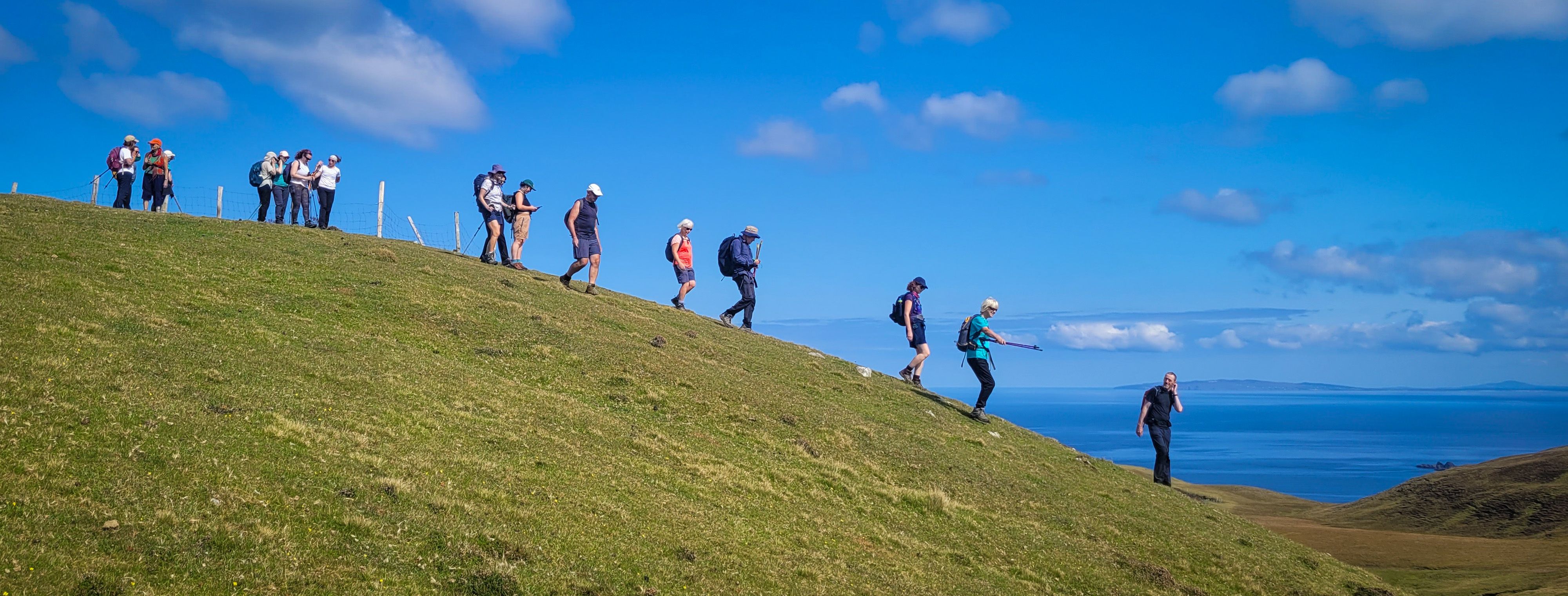 A group of hill walkers walking downhill under the direction of guide Brendan McDyer