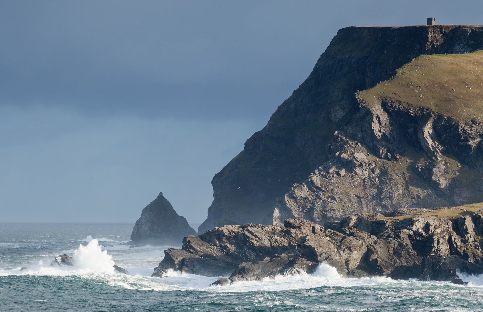 Waves under Glen Head. The Napoleonic signal tower is visible at the summit.