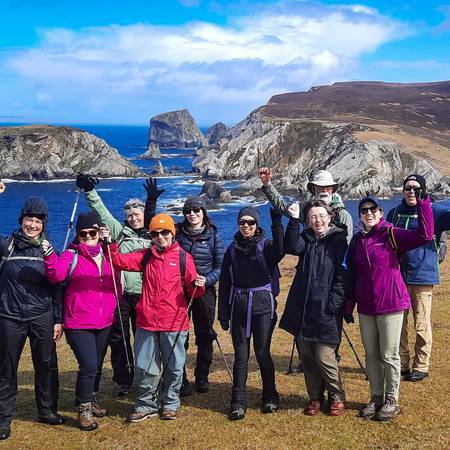 Hill walking group with arms raised; An Port in the background