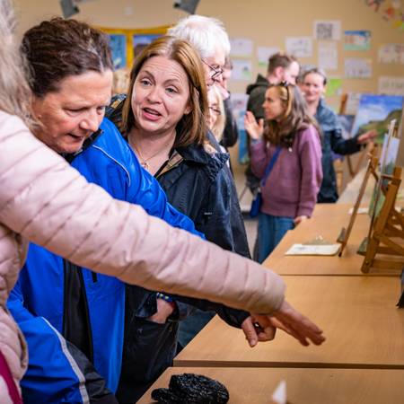 People looking at pictures on display at a painting exhibition in the local primary school